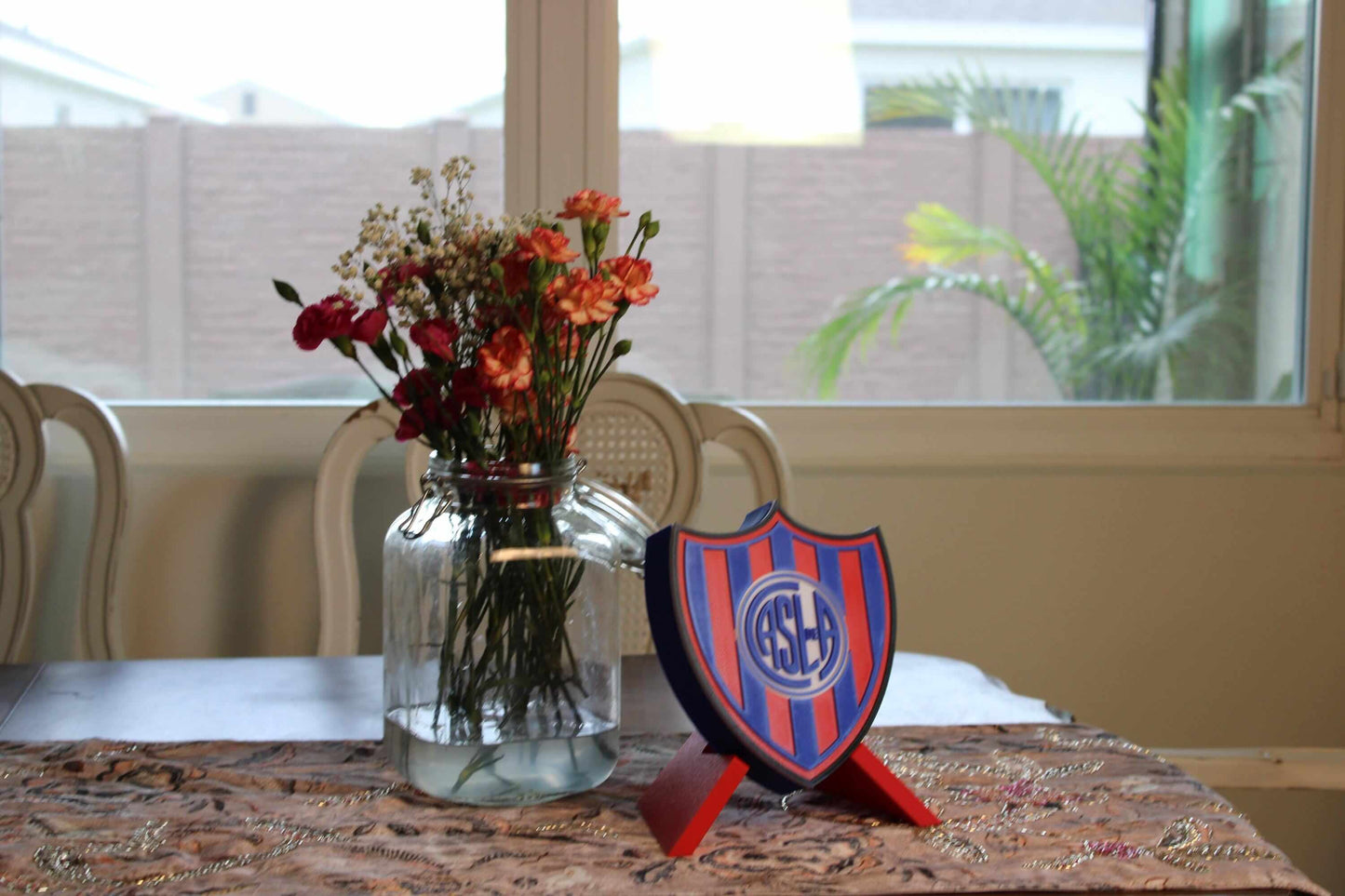 Multicolored 3D printed emblem of San Lorenzo displayed beside a vase of flowers, highlighting fan pride in stylish décor.
