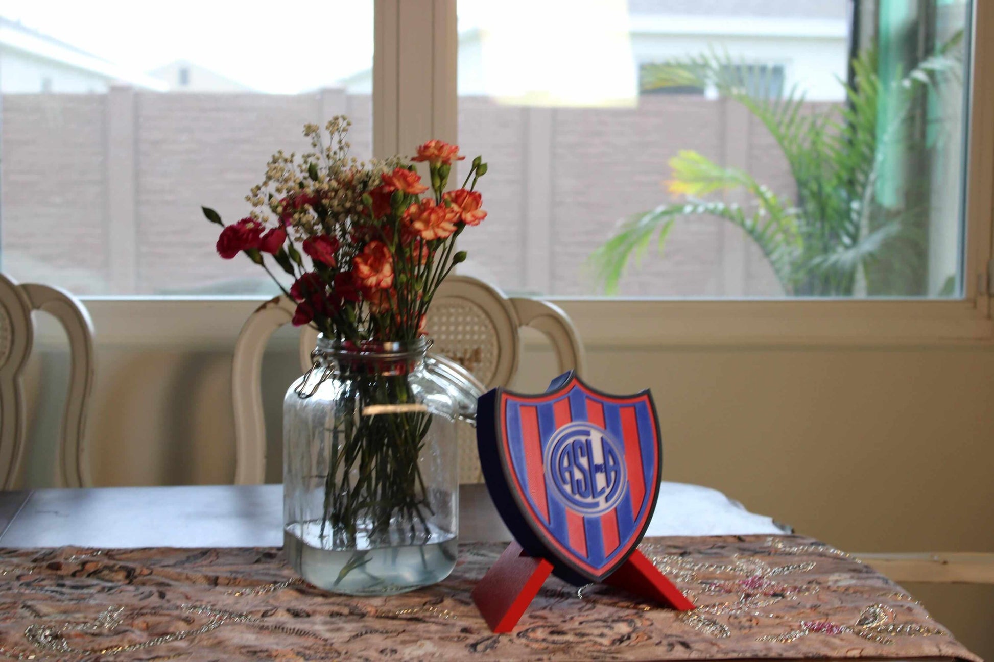 Multicolored 3D printed emblem of San Lorenzo displayed beside a vase of flowers, highlighting fan pride in stylish décor.